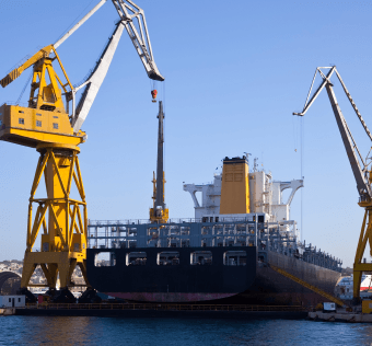 Grues et navire de dragage dans un port, illustrant les projets maritimes et portuaires.