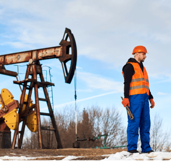 Travailleur sur un site pétrochimique avec pompes et installations, symbolisant les projets industriels complexes.